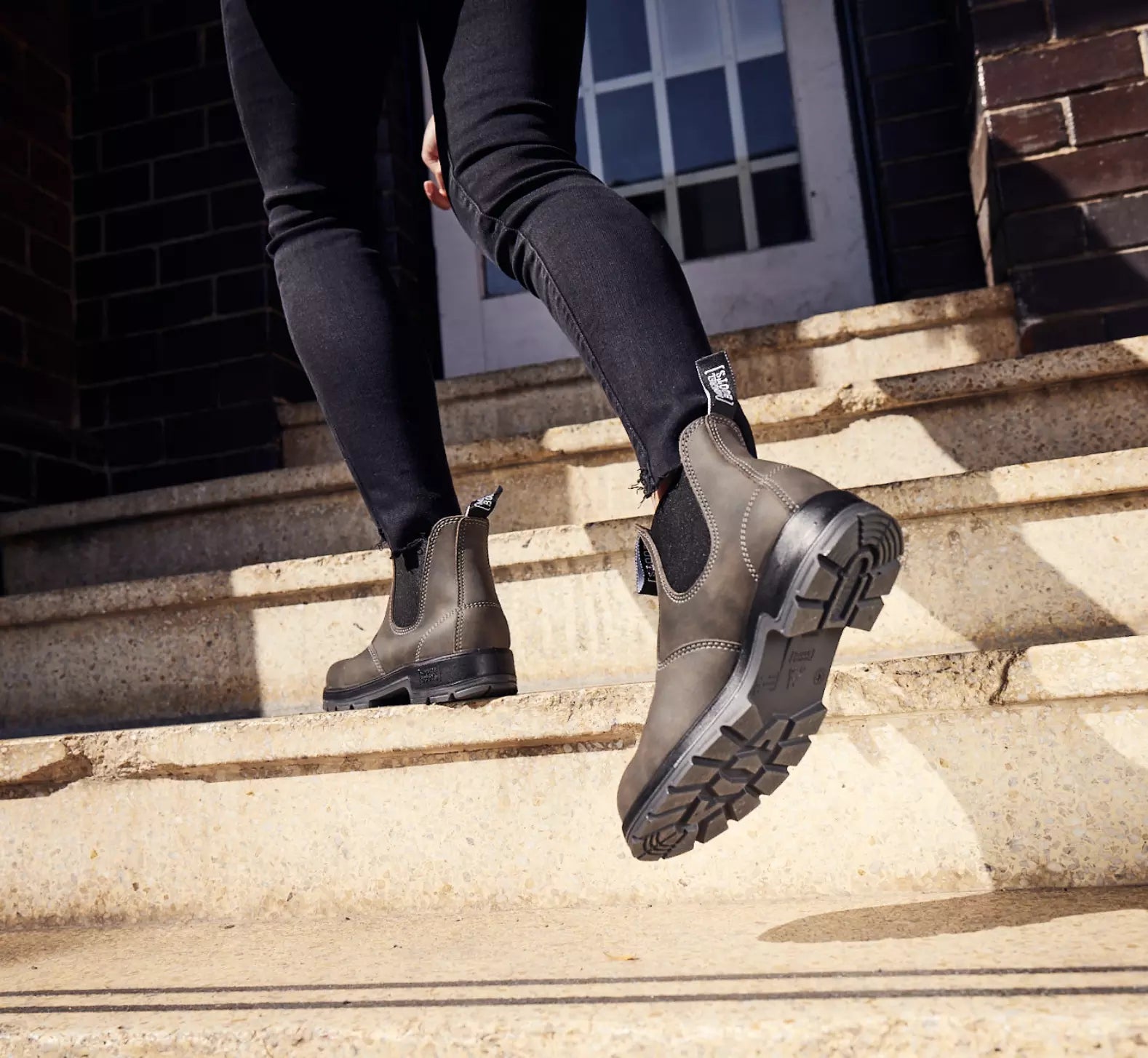 Person wearing black Mongrel elastic-sided boots walking up stairs.